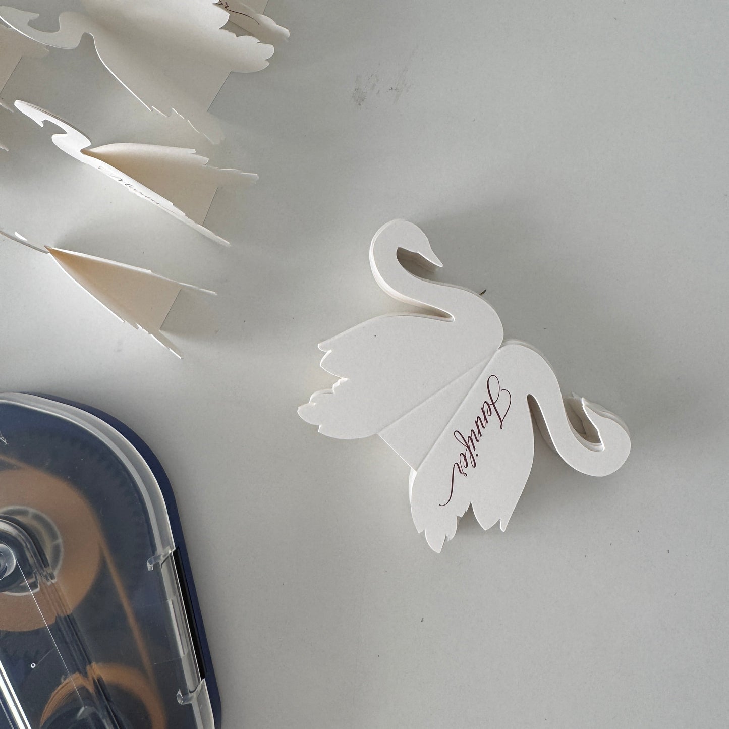 White swan-shaped place card with 'Jennifer' on a white background
