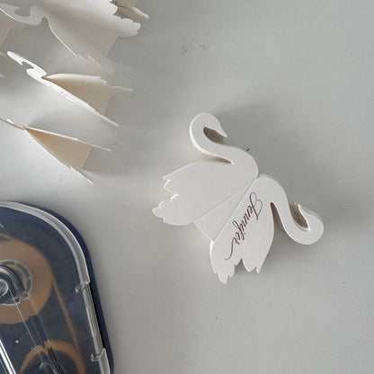 White swan-shaped place card with 'Jennifer' on a white background